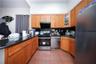 Kitchen with stainless steel appliances, dark countertops, glass insert cabinets, and brown cabinets