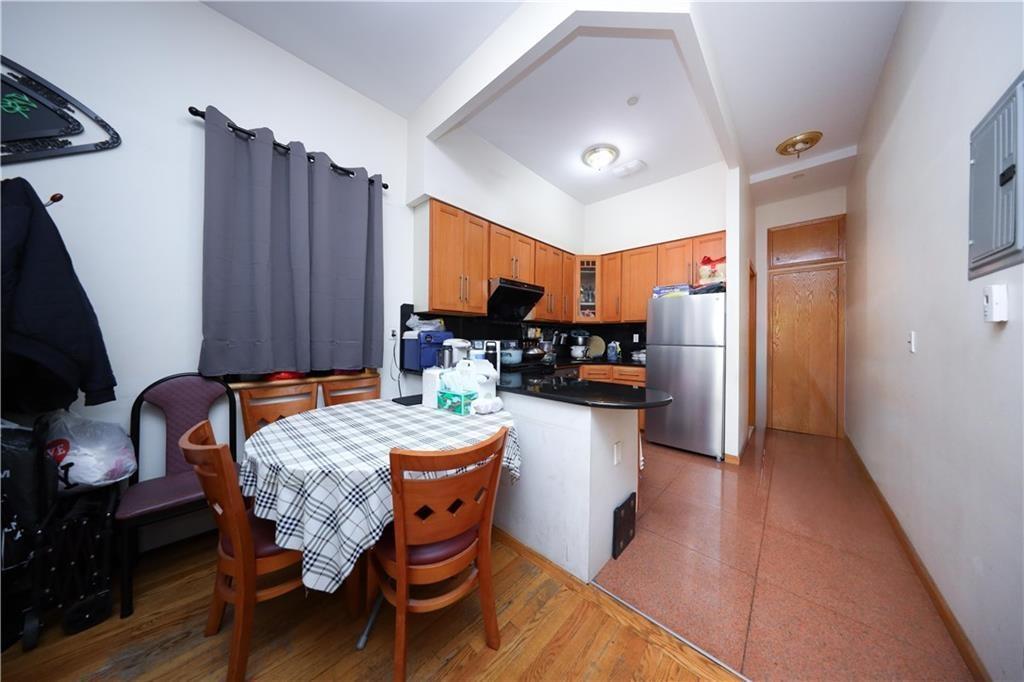 Kitchen featuring freestanding refrigerator, dark countertops, glass insert cabinets, a peninsula, and brown cabinets