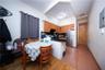 Kitchen featuring freestanding refrigerator, dark countertops, glass insert cabinets, a peninsula, and brown cabinets
