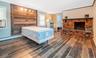 Bedroom featuring wood finished floors, a brick fireplace, an accent wall,