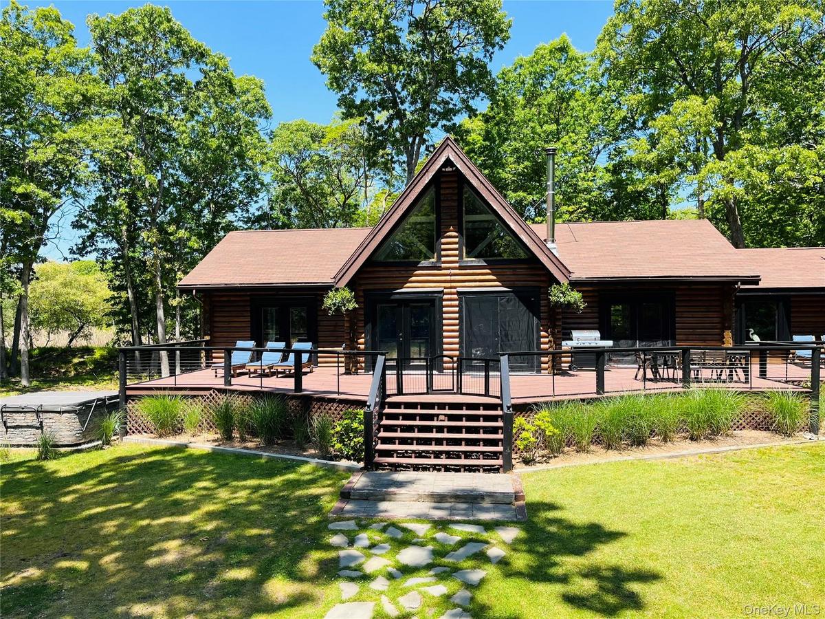 Log home featuring log siding, a front lawn, and a wooden deck