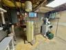 Utility room with electric panel, water heater, and a heating unit