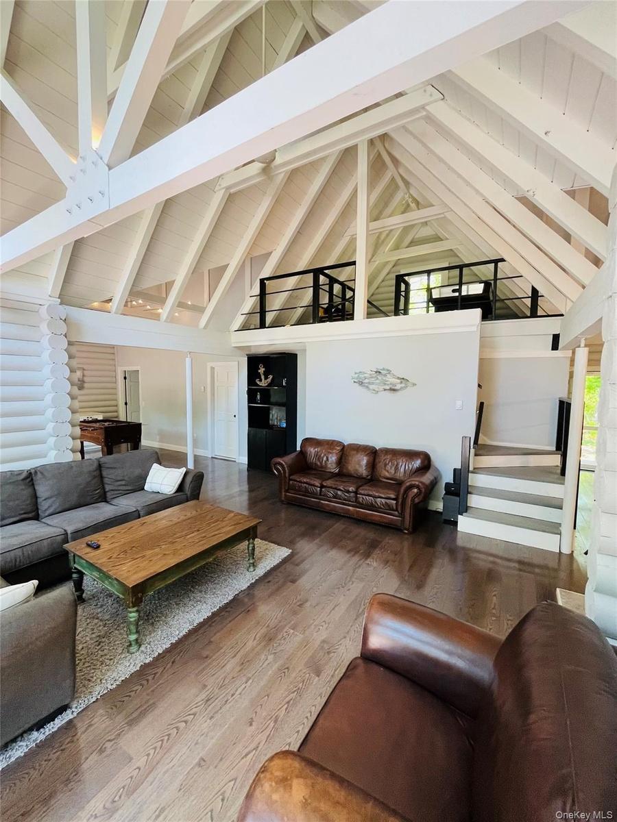 Living area featuring high vaulted ceiling, beam ceiling, and wood finished floors