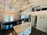Kitchen featuring hanging light fixtures, high vaulted ceiling, a wood stove, a baseboard heating unit, and dark wood-type flooring