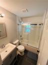 Full bath with vanity, dark tile patterned flooring, and enclosed tub / shower combo