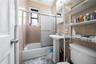 Bathroom featuring enclosed tub / shower combo and tile walls
