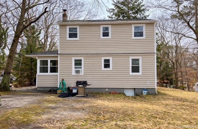 Back of property with a chimney and a lawn
