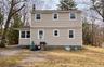 Back of property with a chimney and a lawn