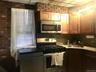 Kitchen featuring stainless steel appliances, tasteful backsplash, dark stone counters, and brick wall