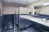 Bathroom featuring double vanity, tile walls, a shower stall, wainscoting, and dark tile patterned flooring
