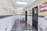 Corridor with a paneled ceiling, dark tile patterned floors, tile walls, elevator, and wainscoting