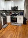 Kitchen with appliances with stainless steel finishes, white cabinetry, light wood-style floors, and tasteful backsplash