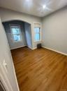 Unfurnished room featuring wood finished floors, radiator heating unit, and arched walkways