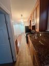 Kitchen featuring dark stone counters, wood tiled floors, stainless steel appliances, glass insert cabinets, and brown cabinets