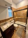 Bathroom with vanity, shower / bath combination with glass door, tile walls, and dark tile patterned flooring