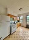 Kitchen featuring white appliances, radiator, light countertops, brown cabinetry, and an ornate ceiling