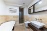 Full bathroom featuring a freestanding bath, tile walls, a wainscoted wall, a shower stall, and vanity