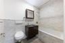 Bathroom featuring vanity, tiled shower / bath combo, tile walls, and wainscoting
