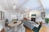 Living area featuring light wood-style flooring, a warm lit fireplace, beamed ceiling, built in features, and track lighting