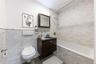 Bathroom with vanity, tile walls, tiled shower / bath, and a wainscoted wall