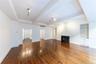 Unfurnished living room featuring beamed ceiling, a fireplace with flush hearth, dark wood-type flooring, built in shelves, and track lighting