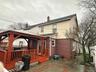 Back of property with a gazebo, a wooden deck, a chimney, a patio, and a shingled roof