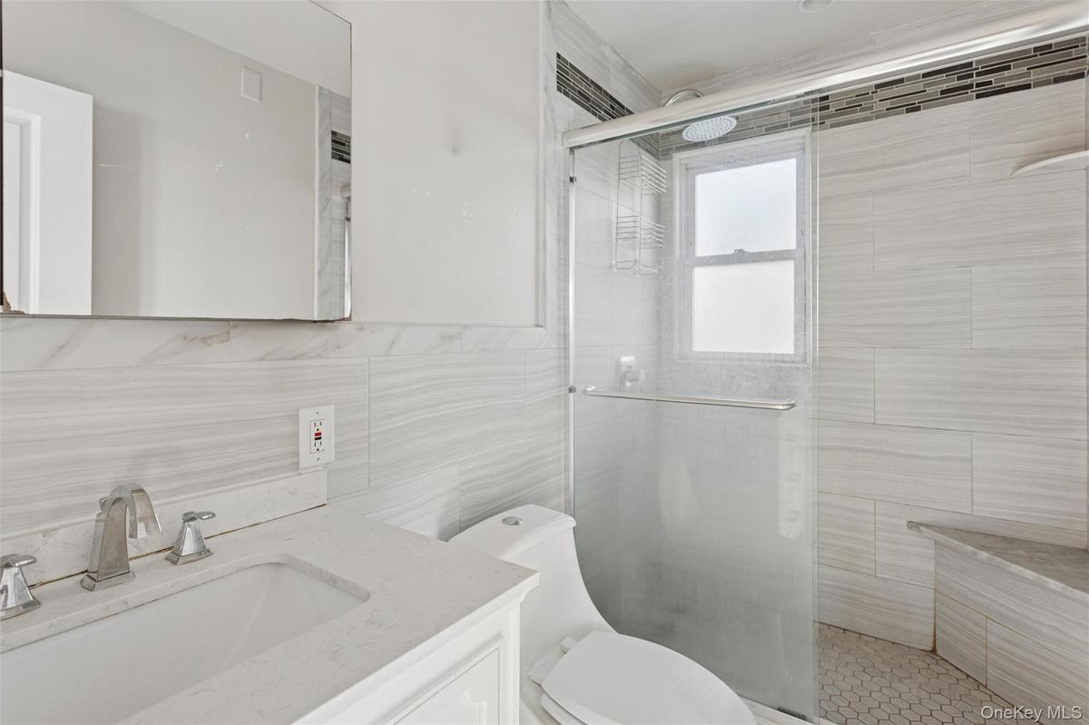 Full bathroom with vanity, a stall shower, and tile walls