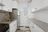Kitchen with white cabinets, wall chimney exhaust hood, and light stone countertops