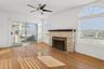 Unfurnished living room featuring a stone fireplace, hardwood / wood-style flooring, and ceiling fan