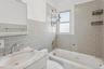 Bathroom with tile walls,  shower combination, and vanity