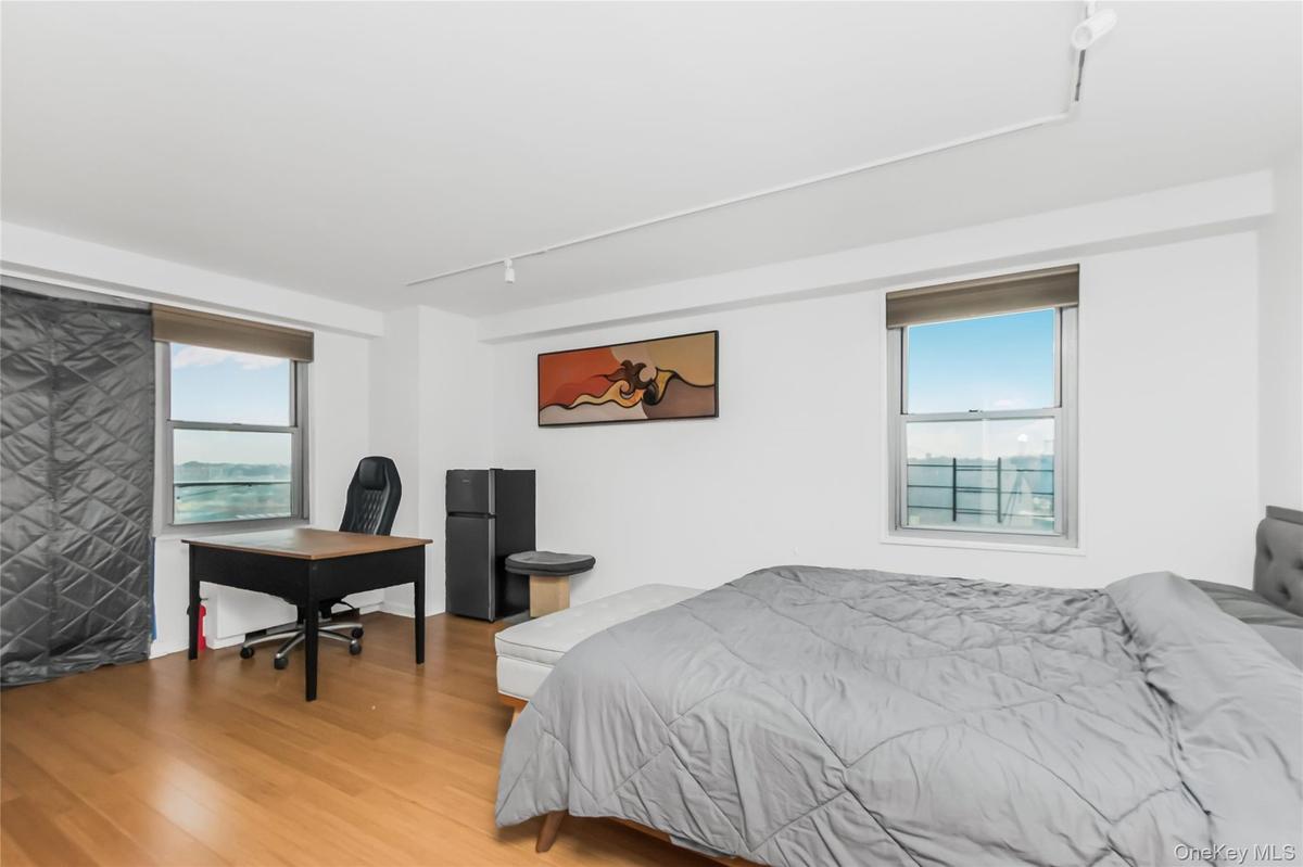 Bedroom featuring track lighting, wood finished floors, freestanding refrigerator, and a desk