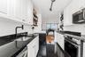 Kitchen with stainless steel appliances, white cabinetry, open shelves, dark stone counters, and rail lighting