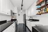 Kitchen with stainless steel appliances, track lighting, white cabinetry, and open shelves
