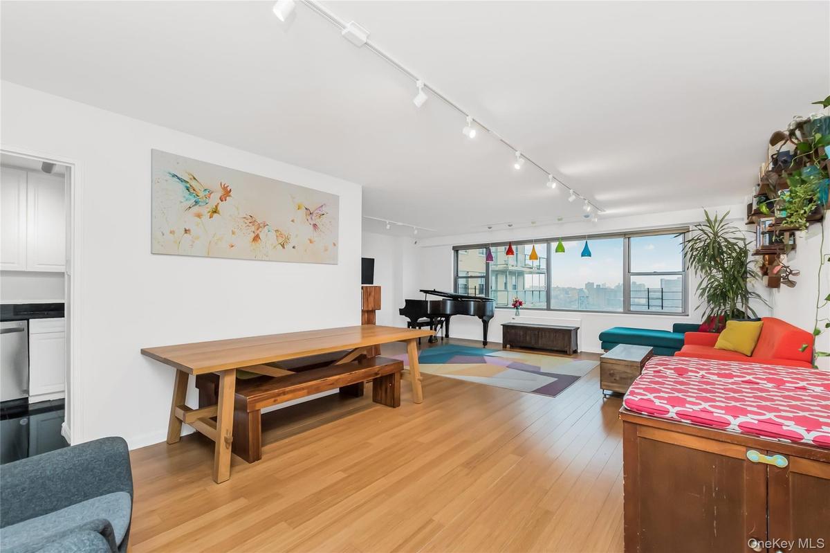 Living room with rail lighting and light wood-type flooring