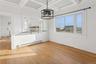 Unfurnished dining area with a chandelier, a baseboard radiator, light wood-style floors, coffered ceiling, and beamed ceiling