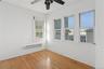Empty room with healthy amount of natural light, a baseboard radiator, a drop ceiling, wood finished floors, and ceiling fan