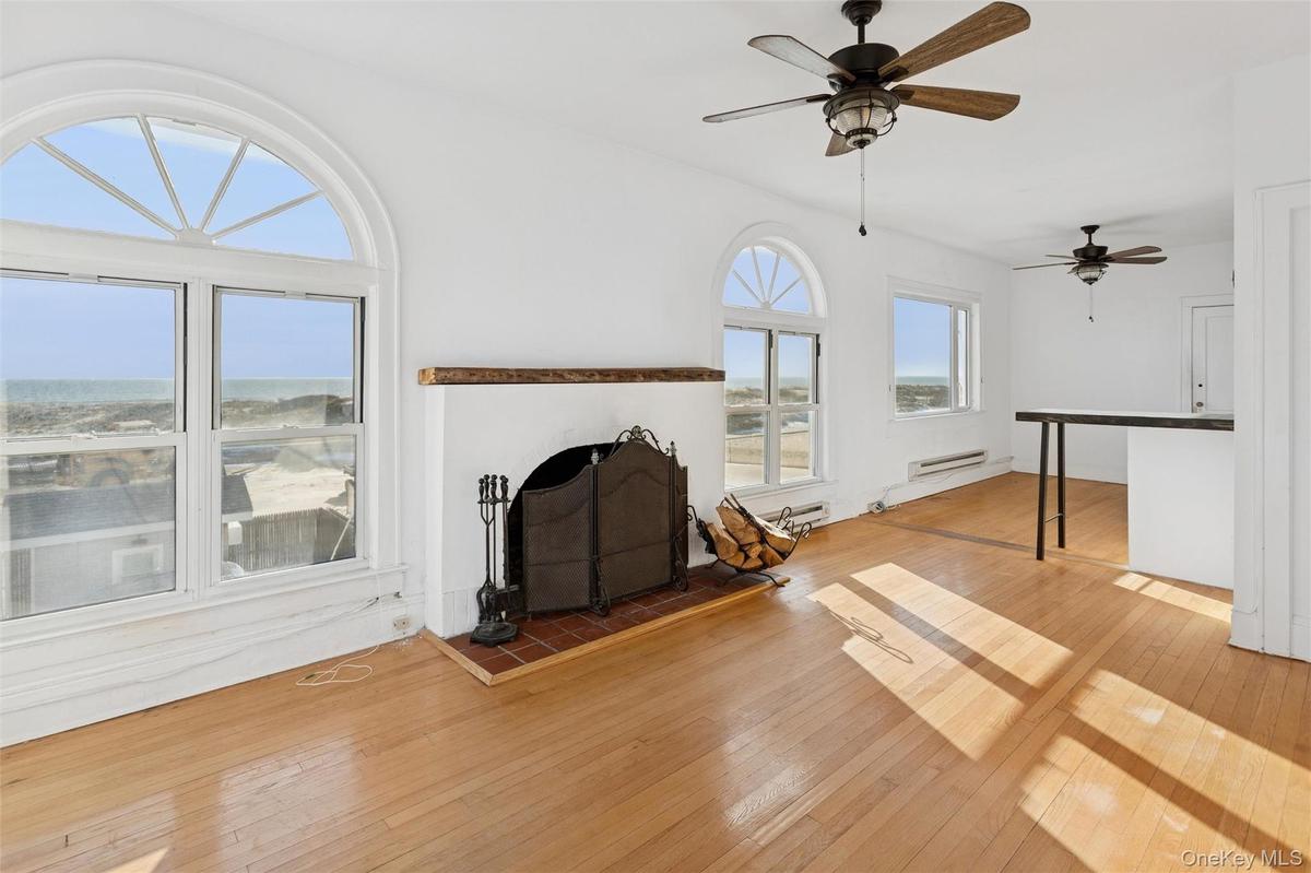 Unfurnished living room featuring hardwood / wood-style flooring, a baseboard heating unit, and a ceiling fan