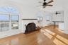Unfurnished living room featuring hardwood / wood-style flooring, a baseboard heating unit, and a ceiling fan