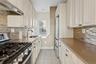 Kitchen with appliances with stainless steel finishes, under cabinet range hood, light stone counters, and light tile patterned flooring