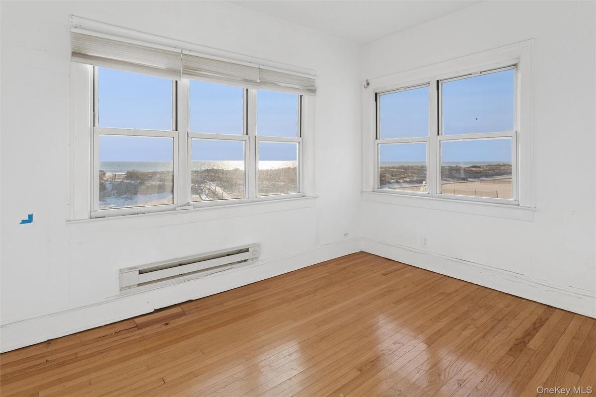 Unfurnished room with baseboard heating and hardwood / wood-style floors