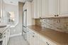 Kitchen featuring stainless steel appliances, a baseboard radiator, and white cabinetry