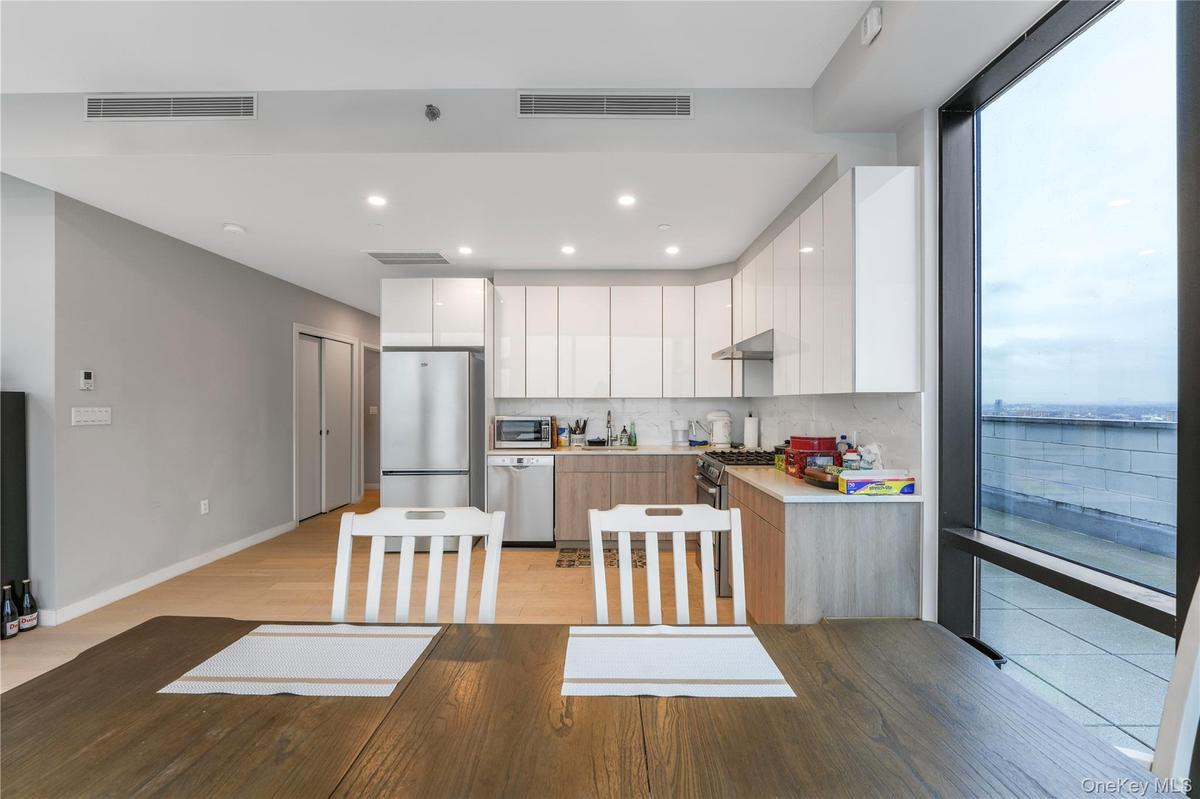 Kitchen with modern cabinets, white cabinetry, light countertops, stainless steel appliances, and recessed lighting