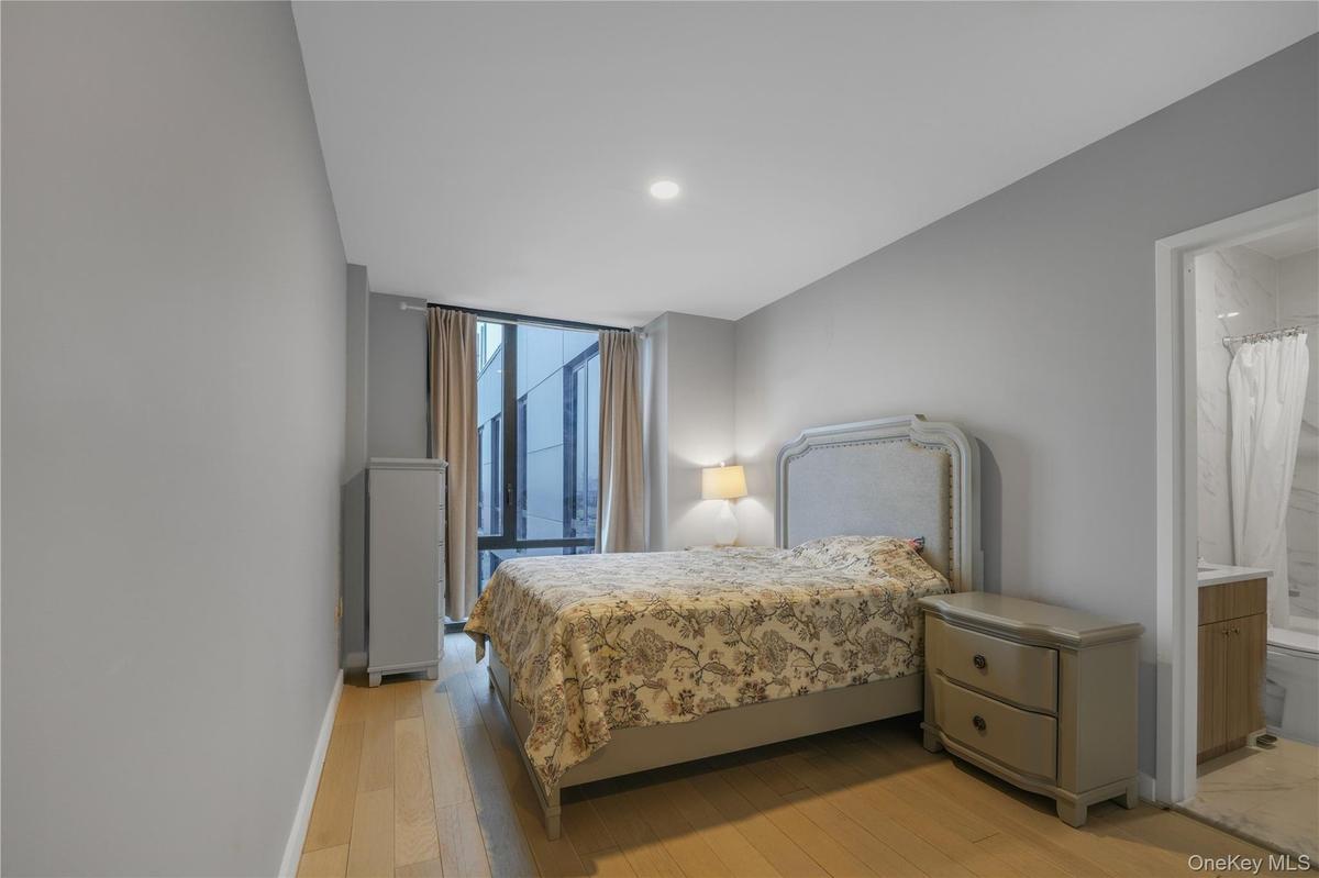 Bedroom with ensuite bath, light wood-style floors, and recessed lighting