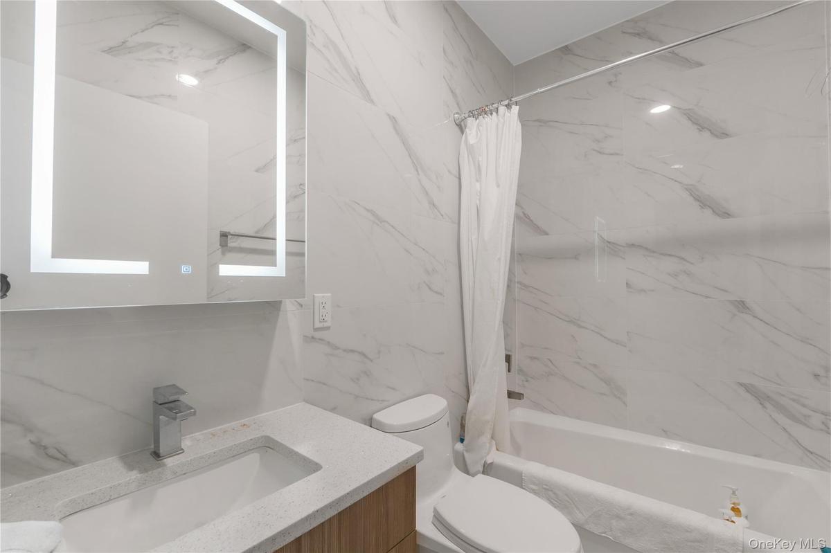 Full bathroom with vanity and a combined bath / shower with marble appearance