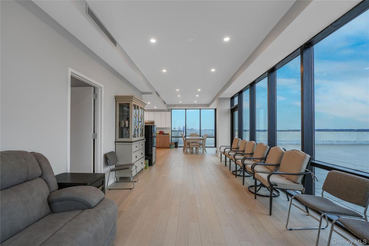 Living room featuring a wall of windows, light wood-style floors, recessed lighting, and a water view