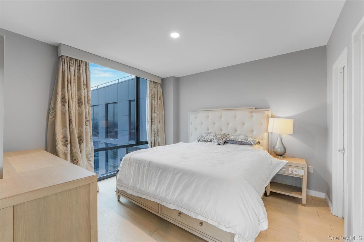 Bedroom with light wood-style floors, floor to ceiling windows, and recessed lighting