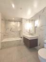 Bathroom featuring tile walls, vanity, and a combined bath / shower with marble appearance