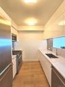 Kitchen featuring modern cabinets, white cabinetry, stainless steel appliances, and light stone counters