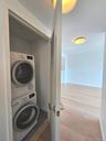 Laundry area with wood finished floors and stacked washer and clothes dryer