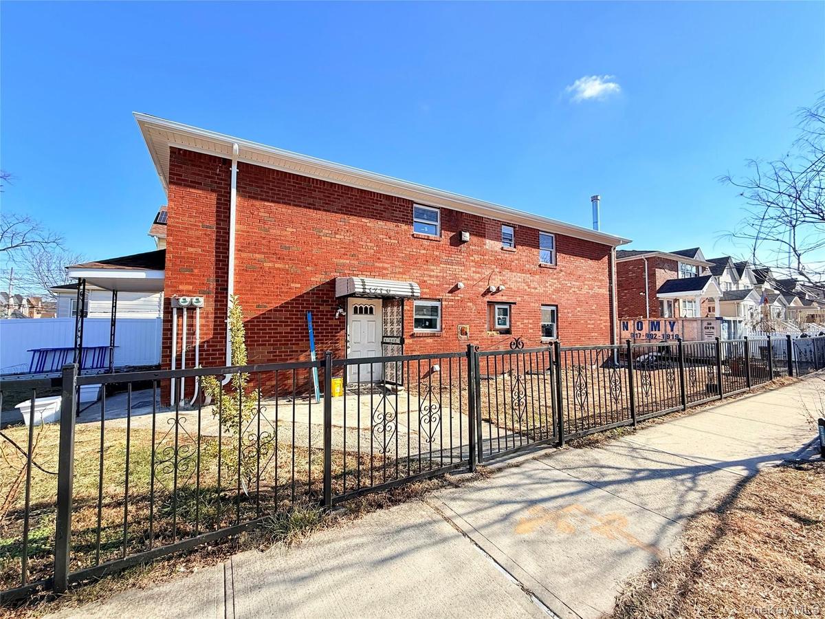 View of side of property with a fenced front yard and brick siding